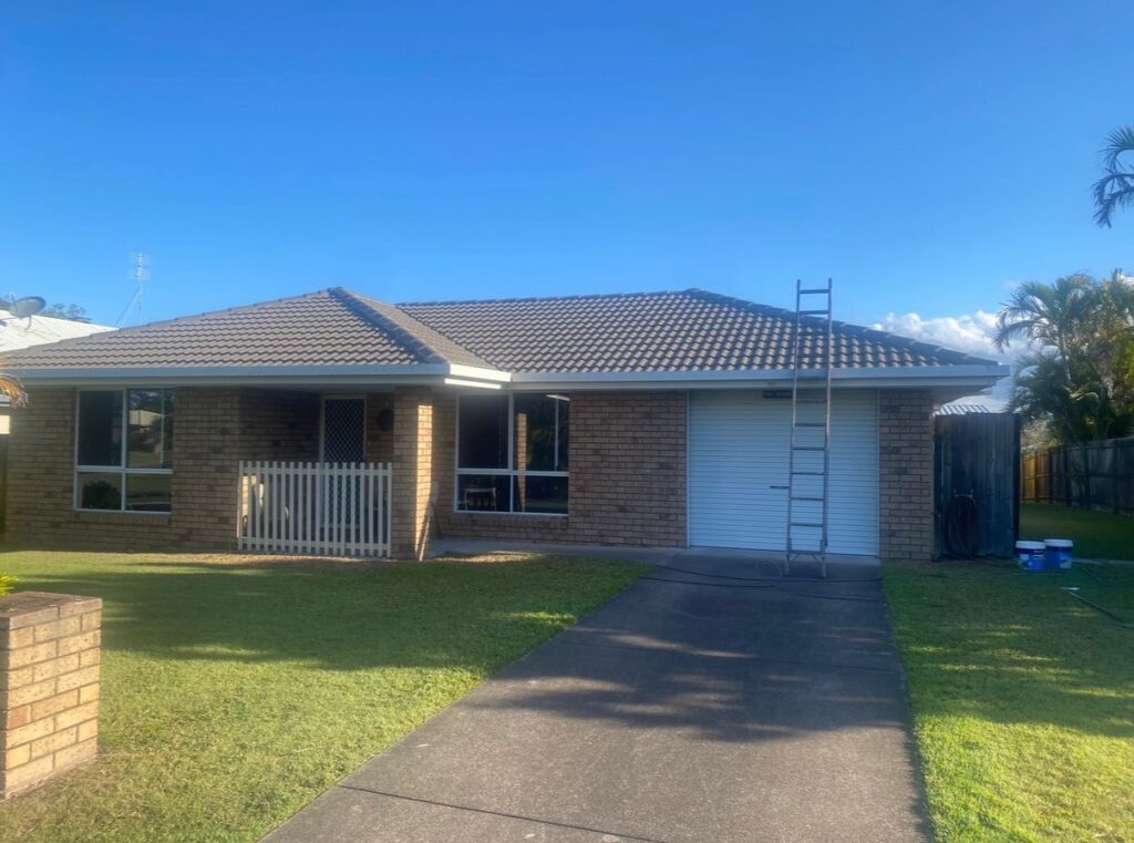 Brick home with a faded brown tile roof prior to professional roof painting